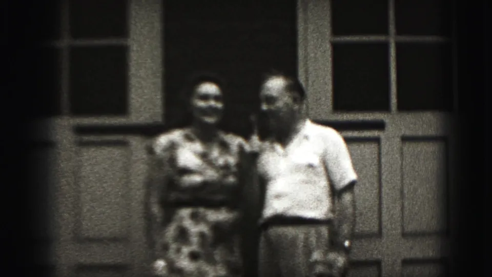 An adult couple stands side by side on the New Cumberland porch, the woman smiling while the man looks toward her.