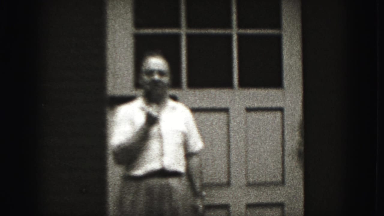 Adult man faces the camera near a paneled door in New Cumberland, Pennsylvania, with a small object held near his mouth.