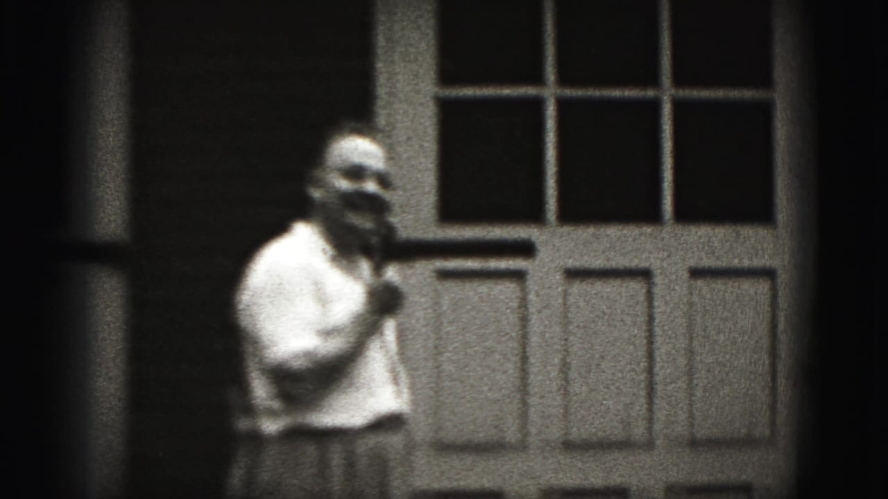Older man in a light shirt stands near a paneled door in 1946 New Cumberland home-movie footage.