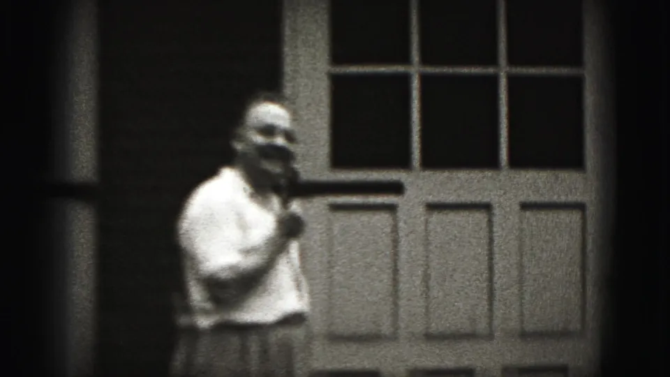 Older man in a light shirt stands near a paneled door in 1946 New Cumberland home-movie footage.