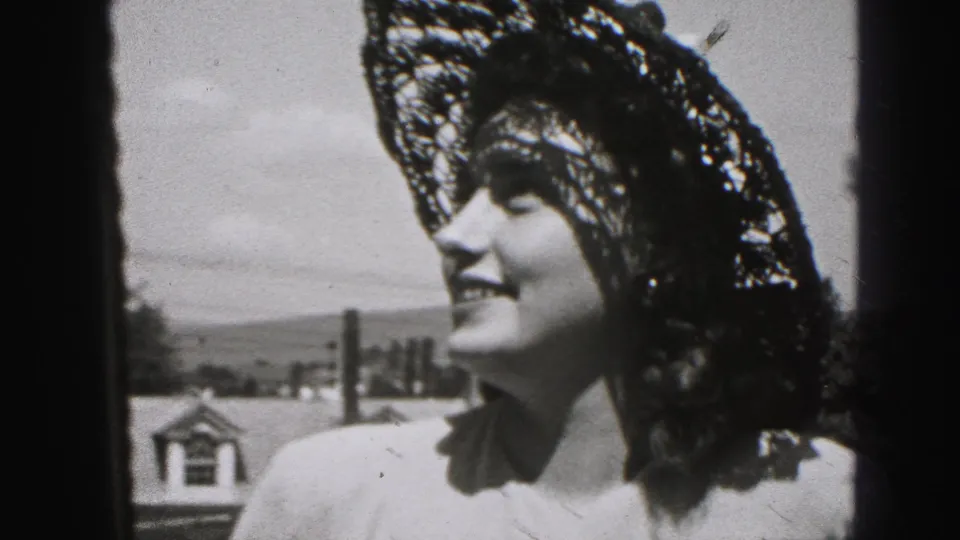 Young woman in New Cumberland, Pennsylvania smiles in bright sunlight while wearing a lace hat in 1946 home-movie footage.
