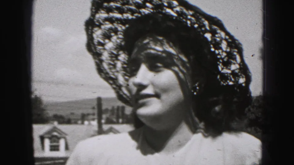 The woman turns slightly toward the camera, her lace hat casting shadows across her face in the New Cumberland outdoor scene.
