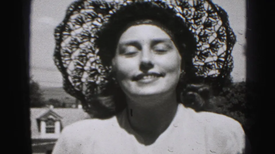 Facing the camera, the woman smiles with eyes closed as sunlight and lace shadows define the 1946 black-and-white frame.