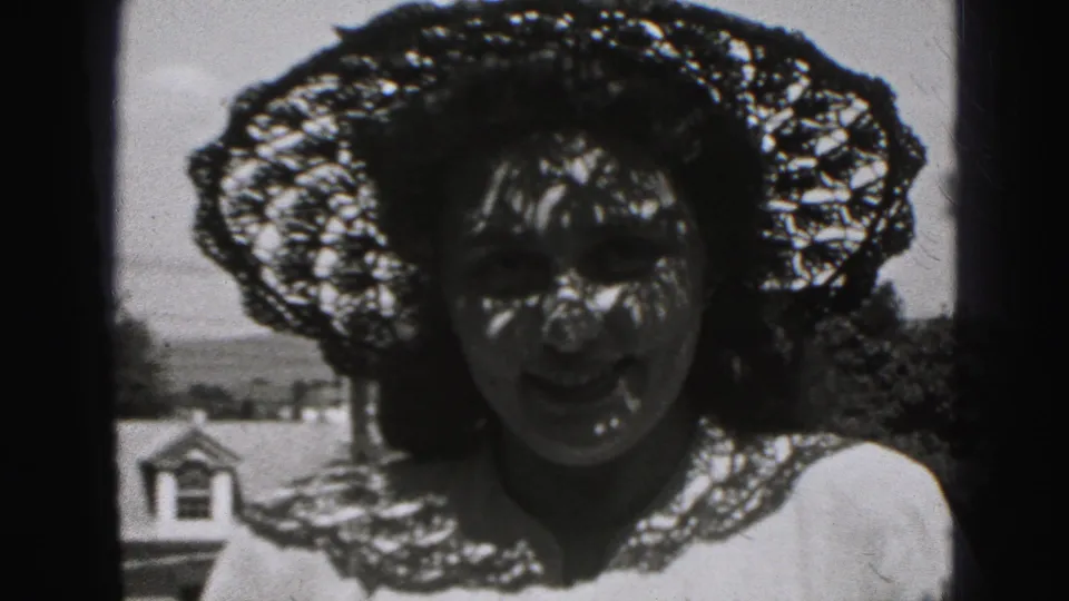 The woman leans forward while her dark hair moves across her face, with the lace hat creating strong shadow patterns.