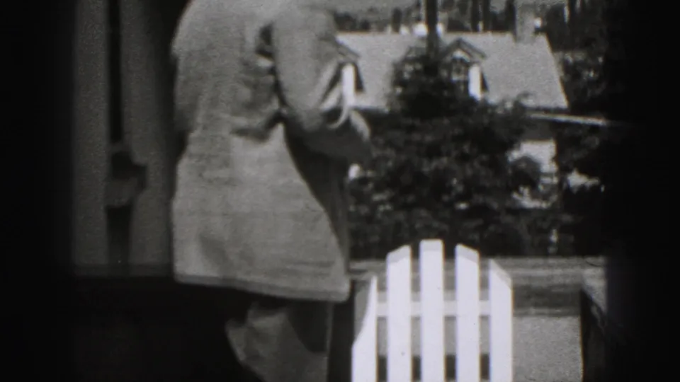 At the end of the 1946 New Cumberland clip, the man is seen from behind near shrubs and a white outdoor chair.