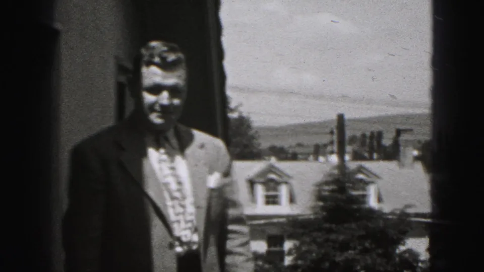 Adult man in a suit and patterned tie faces the camera on a porch or balcony in 1946 New Cumberland.