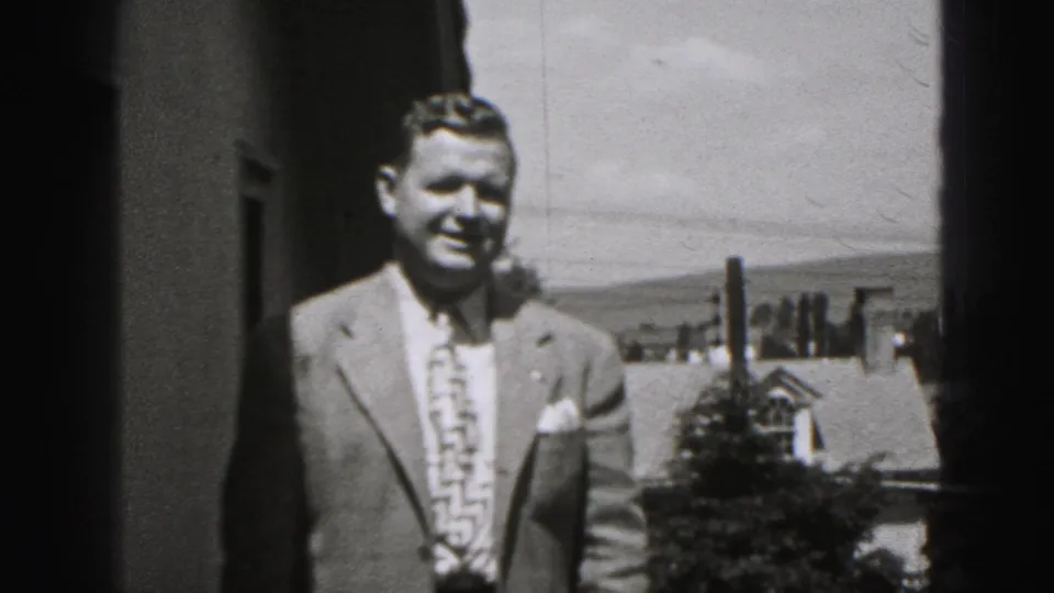Smiling adult man in a light suit stands on a porch or balcony with New Cumberland homes behind him.