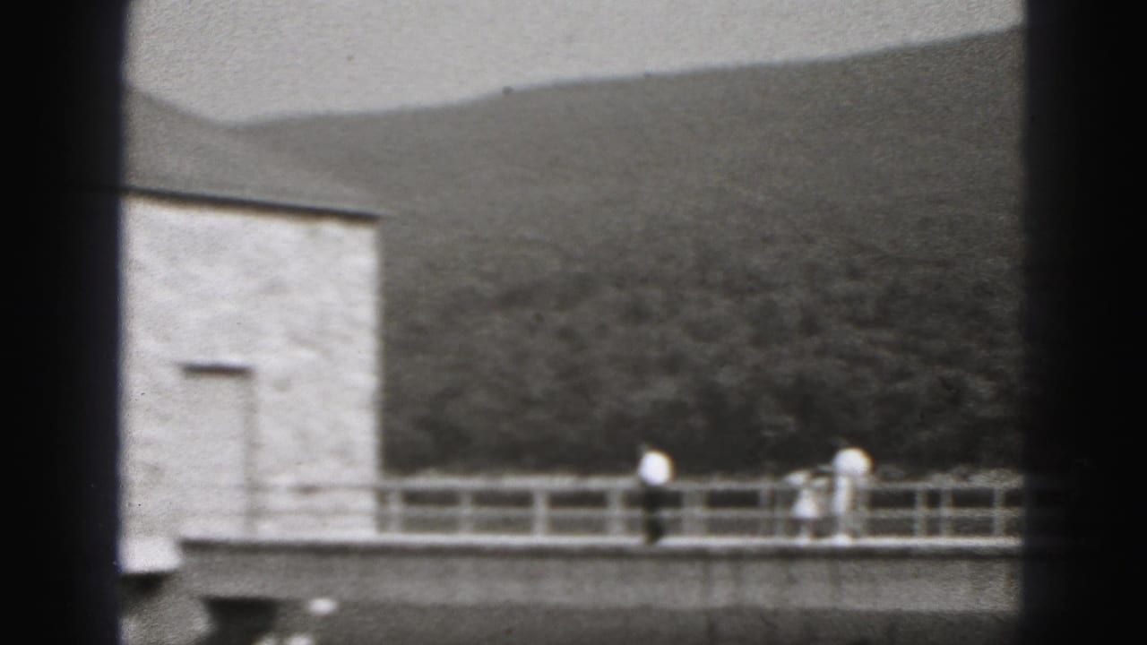 A 1946 New Cumberland riverfront view shows walkers on a bridge near a stone pump house with wooded hills behind it.