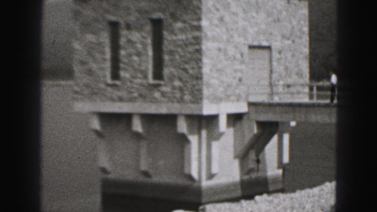 Stone riverside structure beside water with a gravel path and railing nearby.