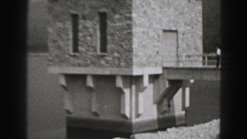 1946 New Cumberland home-movie frame showing a stone dam or riverside structure near water and a gravel path.