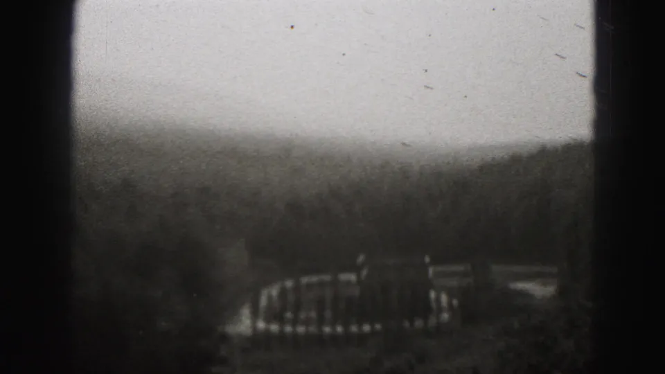1946 8mm home-movie frame from New Cumberland showing misty wooded hills and a distant built structure through soft focus.