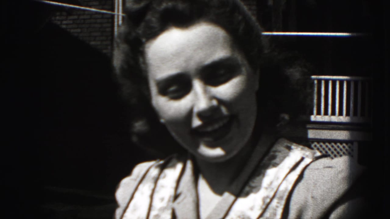 Young woman turns toward the camera with a slight smile beside a porch railing.