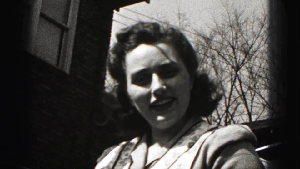 A woman in a patterned apron faces the camera during a 1946 outdoor home-movie moment in New Cumberland, Pennsylvania.