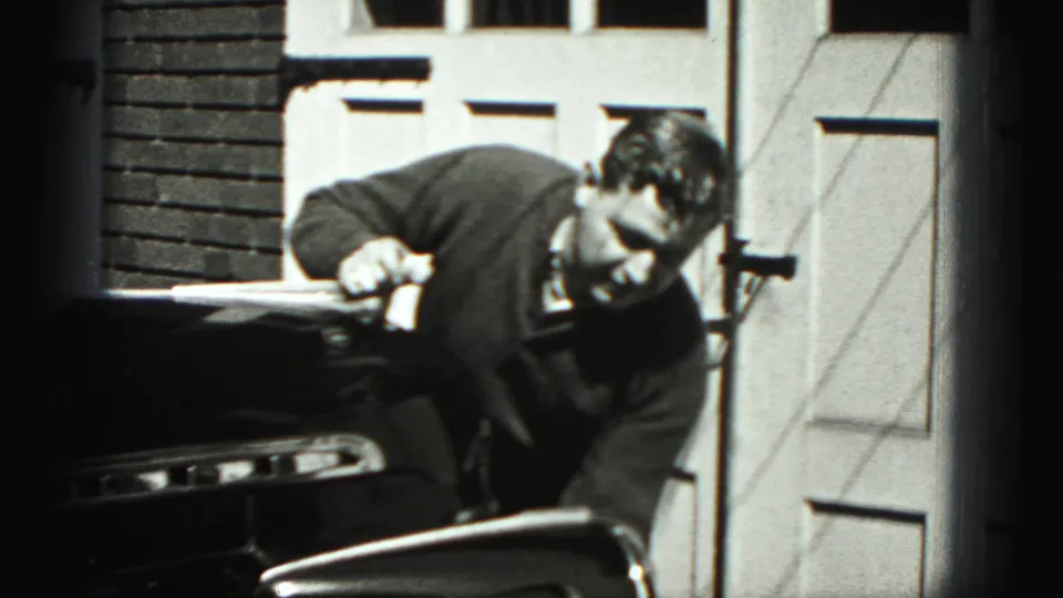 In New Cumberland, Pennsylvania, a man in dark clothing leans over the front of a vintage car in 1946 home-movie footage.