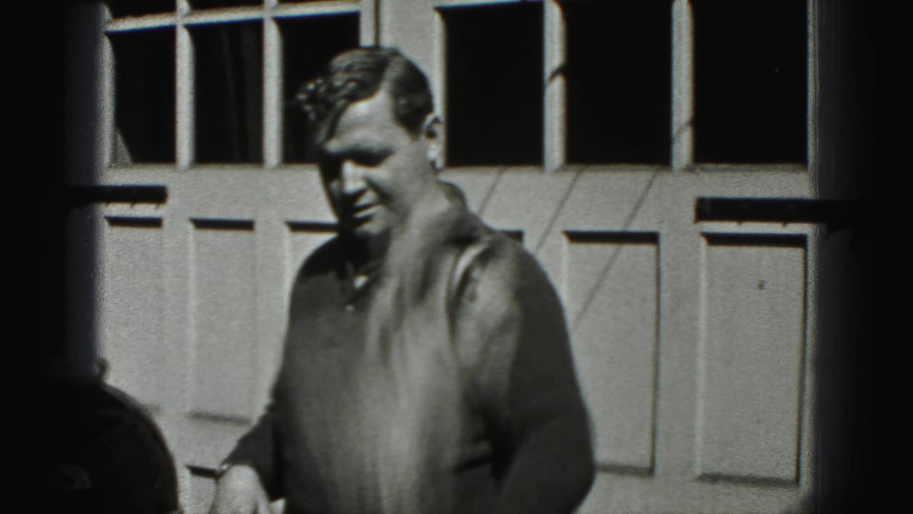 An adult man in a dark sweater stands outside a garage door in New Cumberland, Pennsylvania, in 1946 footage.