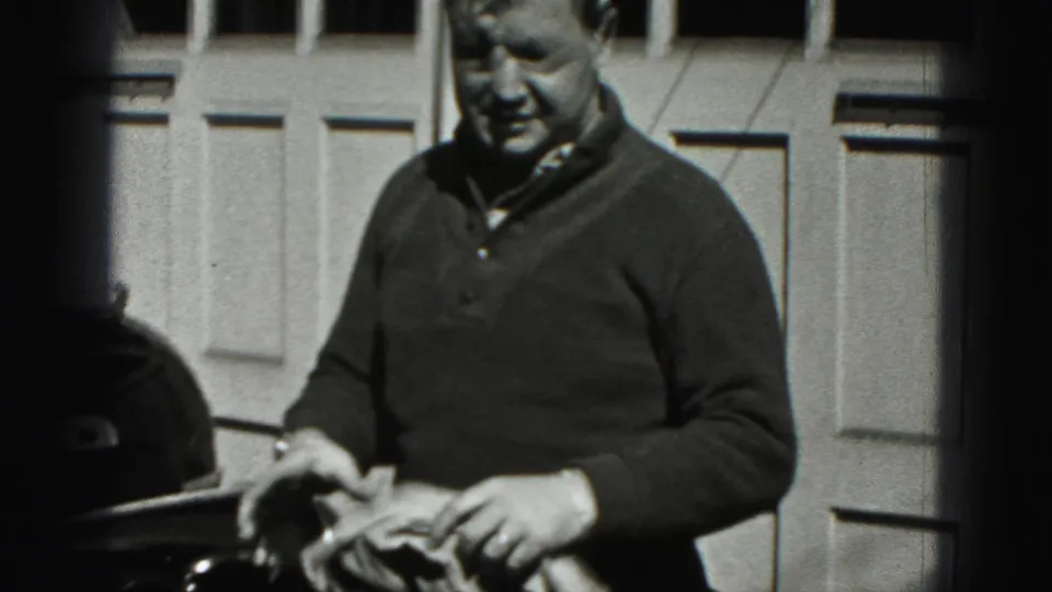 The man handles a small towel outside the paneled garage door in this 1946 New Cumberland home movie.