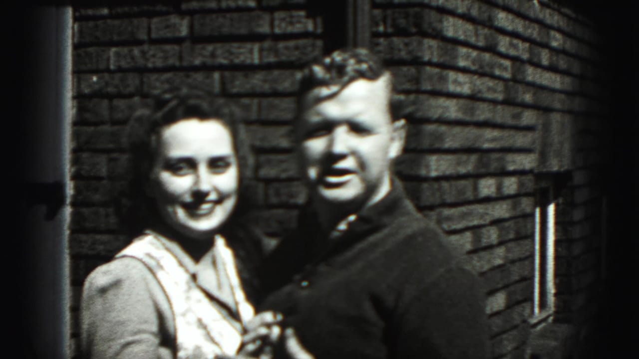 Adult woman and man smiling together against a brick wall.