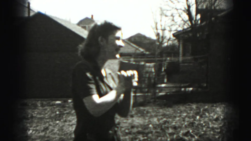 Woman seen in profile in a 1946 New Cumberland yard, with houses and bare trees behind her.