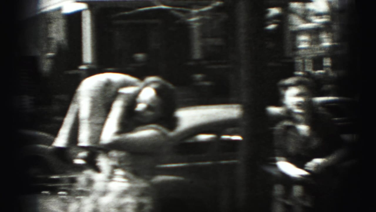 Woman bends beside a small child near a parked car on a residential street.