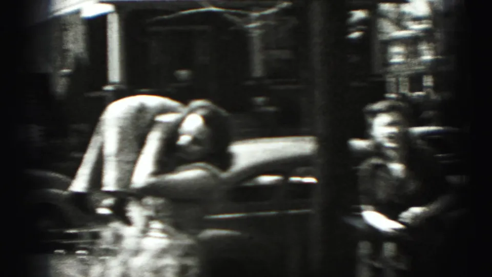 In 1946 New Cumberland, Pennsylvania, a woman bends toward a small child near a curbside car on a residential street.