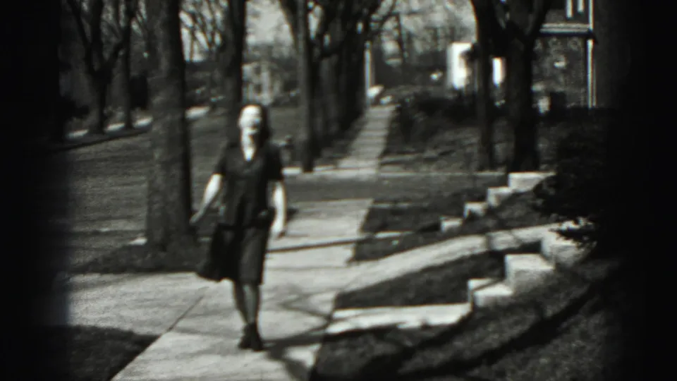 In New Cumberland, Pennsylvania home-movie footage from 1946, a young woman walks along a residential sidewalk toward the camera.