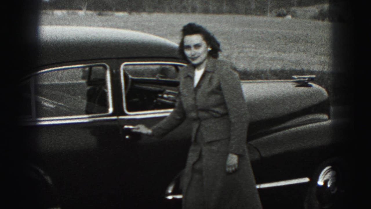 In 1946 New Cumberland home-movie footage, a woman smiles toward the camera while standing beside a dark mid-century sedan.