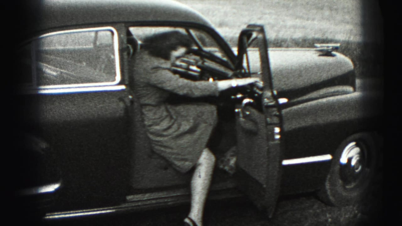 The woman climbs into the driver's side of the dark sedan, with the open door and car interior visible.