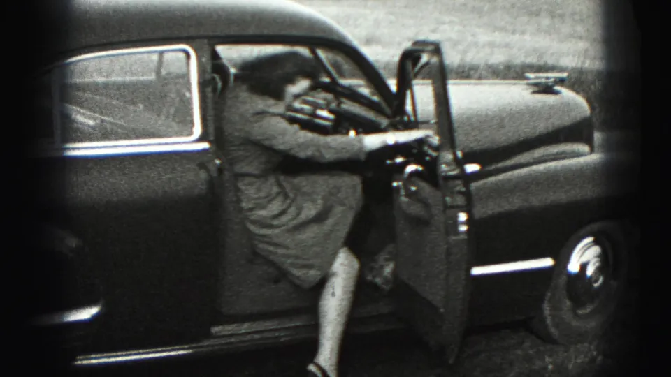 The woman climbs into the driver's side of the dark sedan, with the open door and car interior visible.