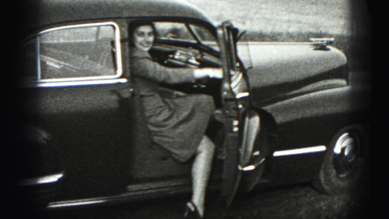 In 1946 New Cumberland footage, a woman smiles beside an open door of a dark rounded sedan.