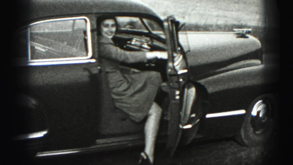 In 1946 New Cumberland footage, a woman smiles beside an open door of a dark rounded sedan.