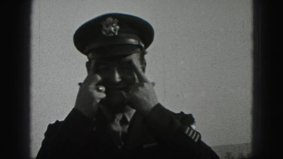 The uniformed man raises both hands to his cap, adjusting it in a candid 1946 outdoor home-movie frame.