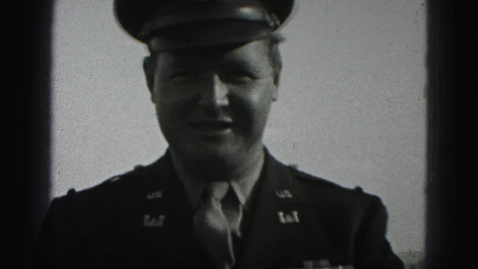 A uniformed officer in a peaked cap smiles in soft black-and-white 8mm footage from New Cumberland, Pennsylvania.