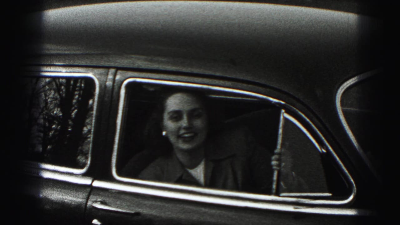 A woman in a coat looks out from a car window in 1946 New Cumberland, Pennsylvania home-movie footage.