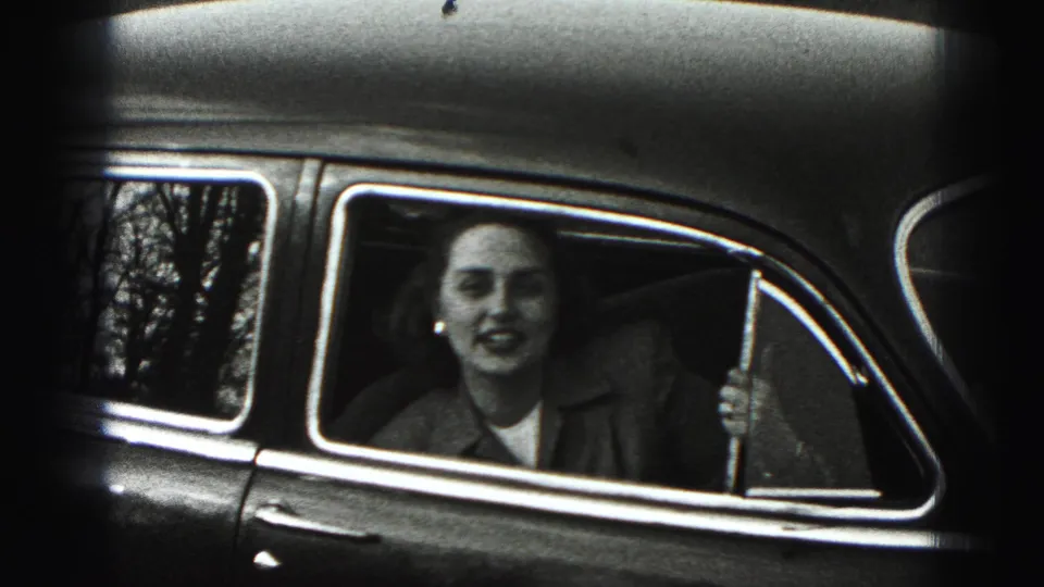 In New Cumberland, Pennsylvania, a young woman smiles from an open rear car window in 1946 black-and-white 8mm footage.