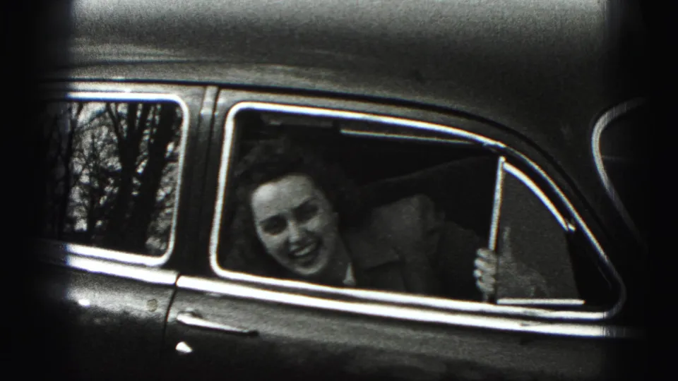In 1946 New Cumberland home-movie footage, a woman smiles from the back seat window of a rounded vintage car.