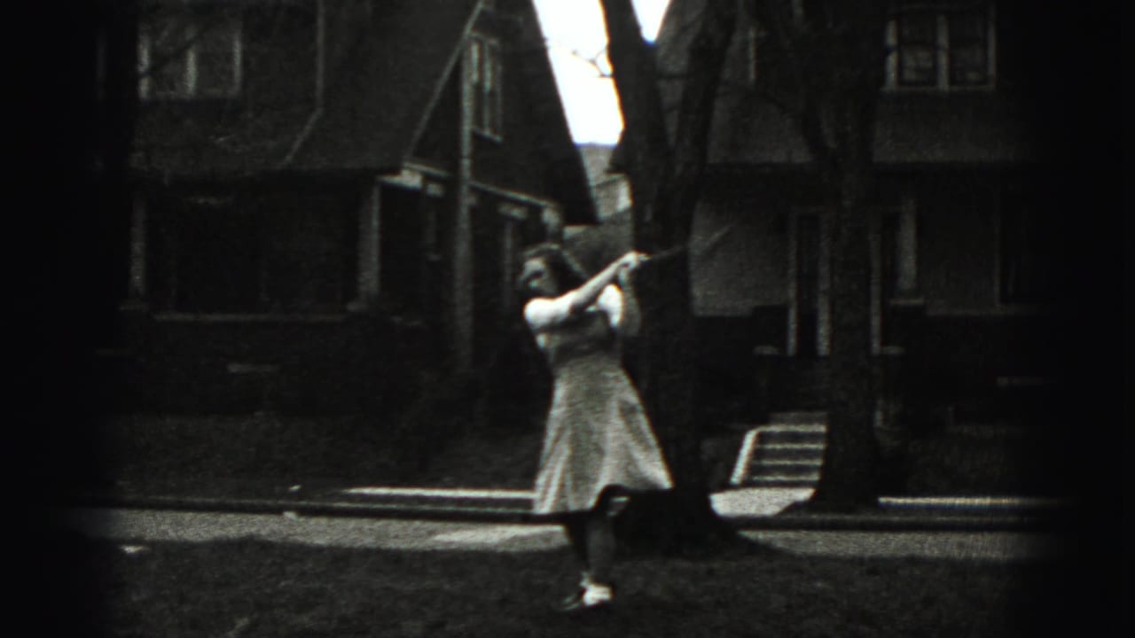 In the residential New Cumberland scene, a woman in a light dress holds a golf club on a lawn near houses and bare trees.