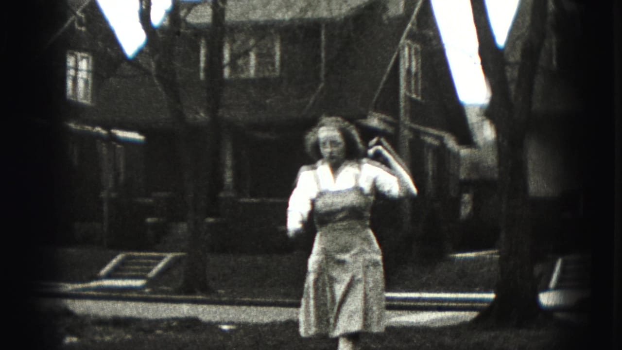 In the 1946 New Cumberland home-movie frame, the young woman nears the camera with a long stick or golf club held at her shoulder.