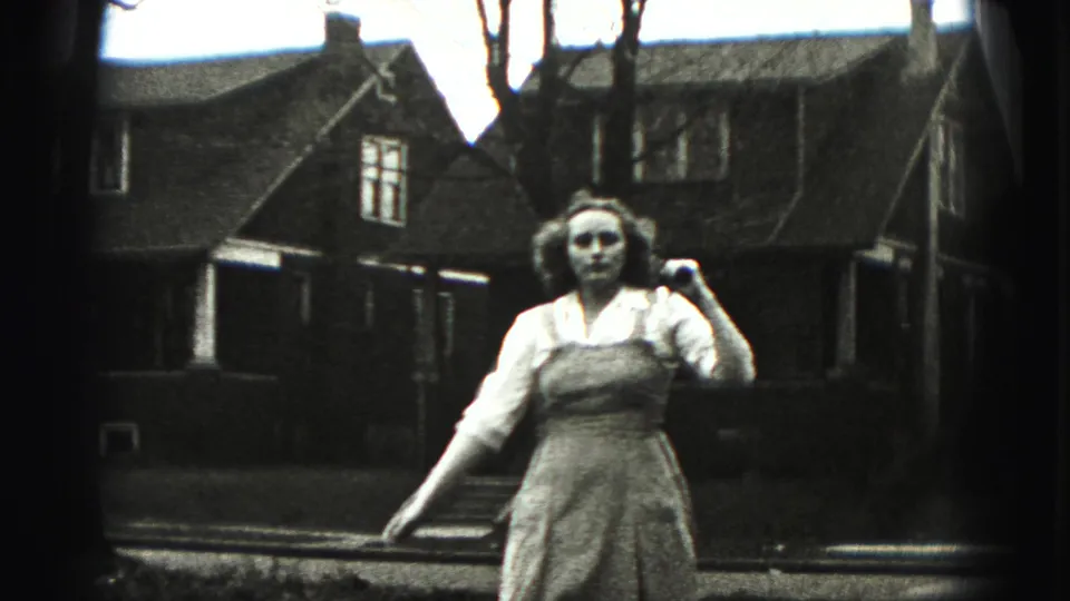 A closer 1946 New Cumberland frame shows the young woman holding the stick at shoulder height in front of a residential house.