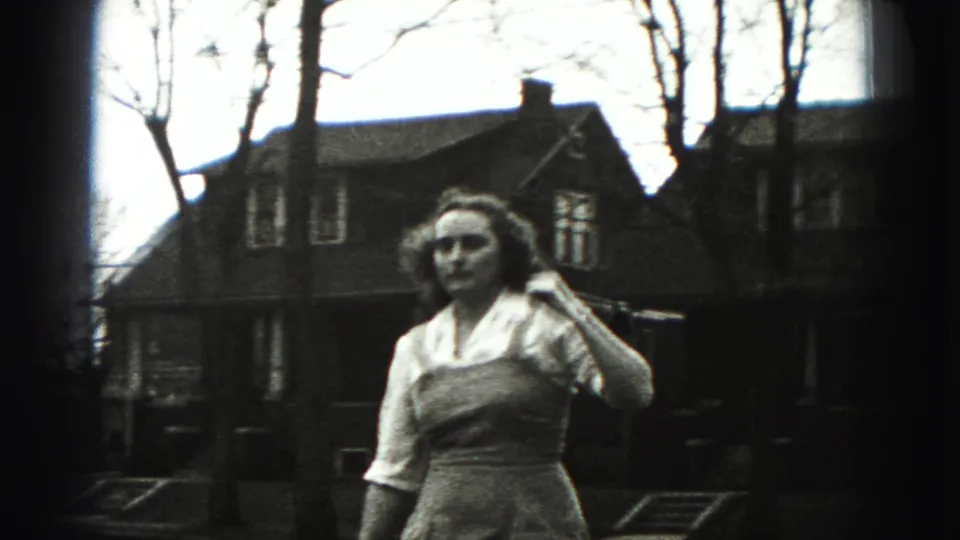 The young woman in the New Cumberland 1946 footage faces slightly aside while holding a long stick or golf club near her shoulder.