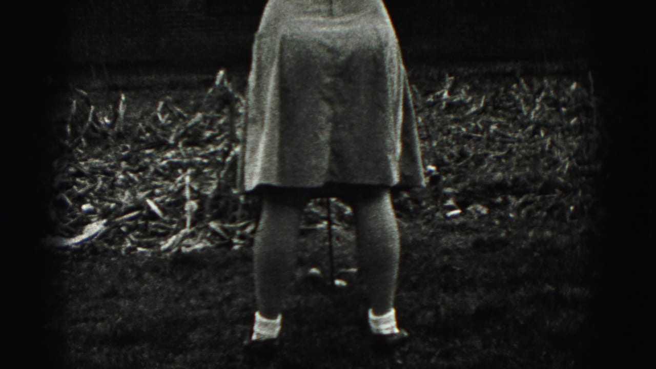 In 1946 New Cumberland home-movie footage, a woman is seen from behind in a yard holding a golf club near a brick house.