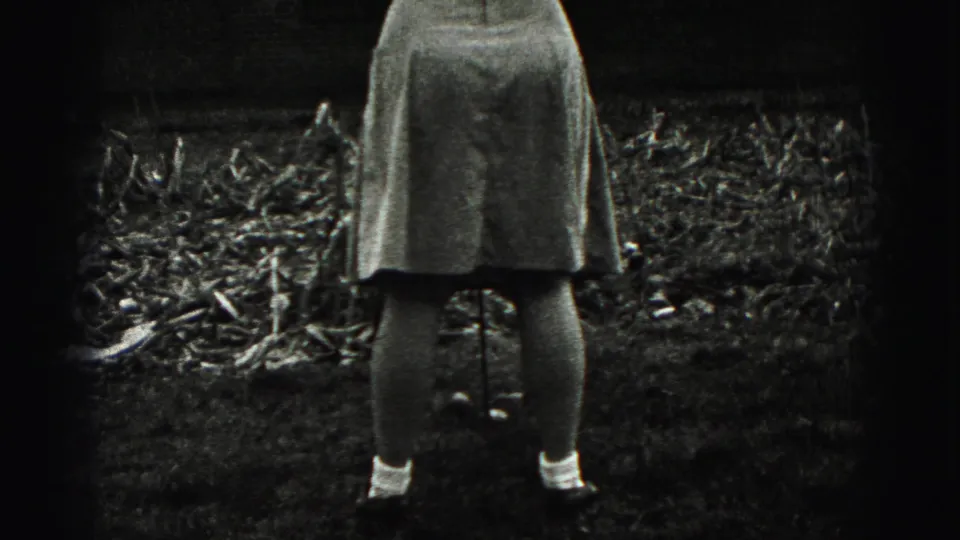 In 1946 New Cumberland home-movie footage, a woman is seen from behind in a yard holding a golf club near a brick house.