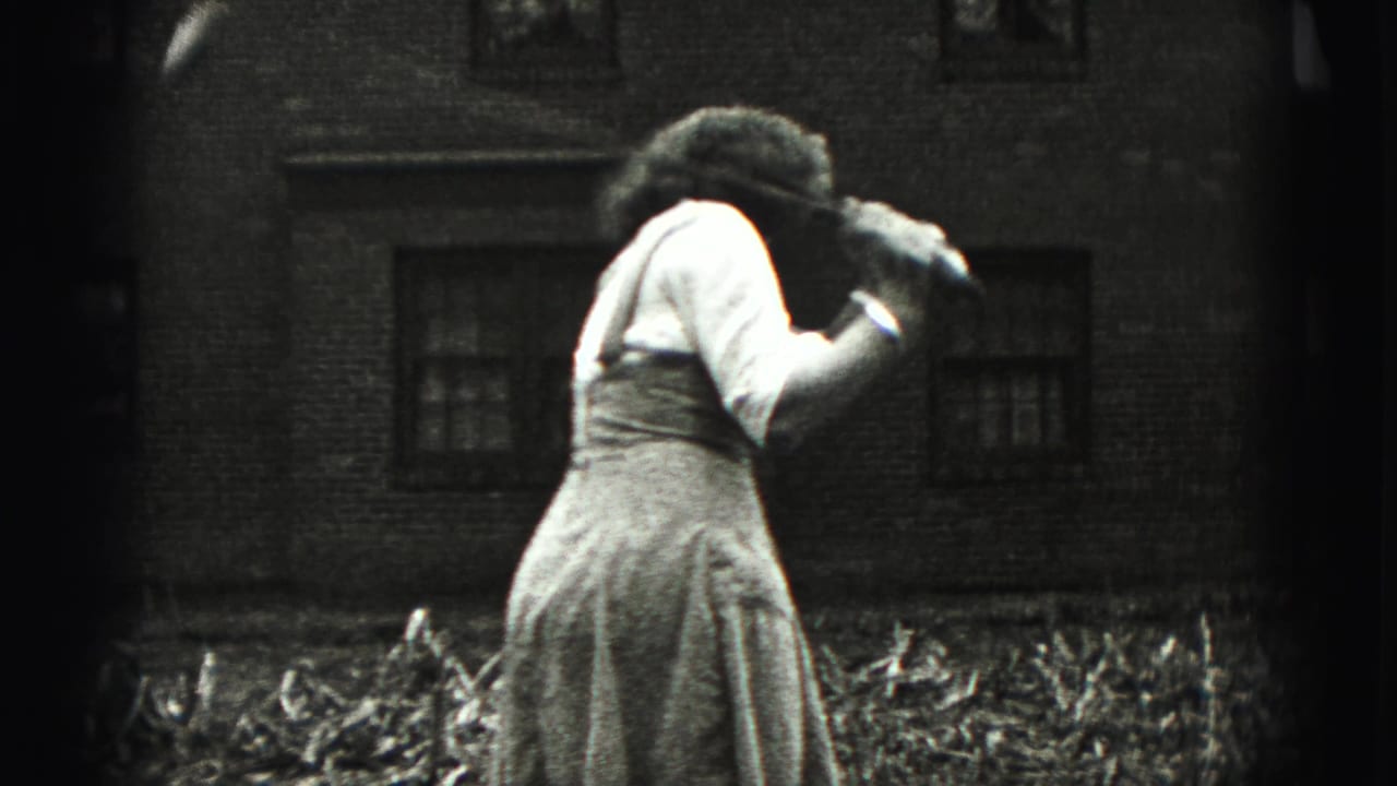The woman leans forward during the golf practice scene, filmed close to a brick residential wall in 1946 home-movie footage.