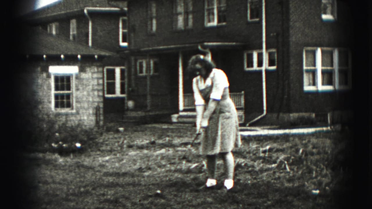 A woman practices a golf swing in the yard of a New Cumberland residence, with house windows and bare ground visible around her.
