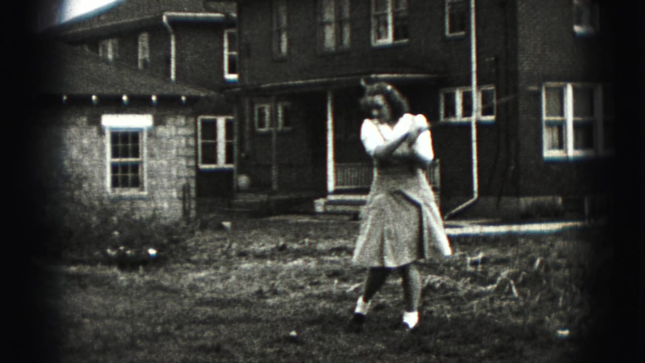 A woman in a skirt stands with her arms near her shoulder after a golf swing in a 1946 backyard scene.
