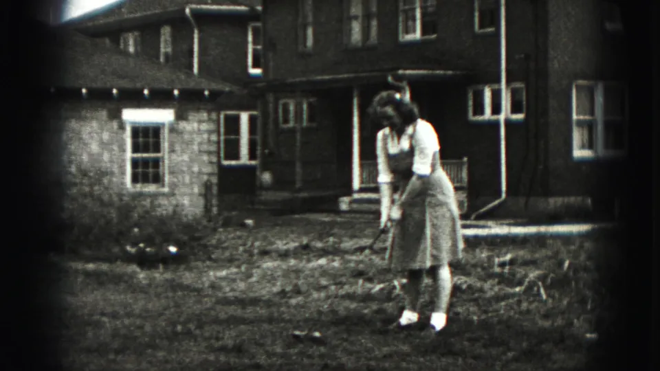A woman resets her golf club on a modest New Cumberland lawn, with a residential exterior behind her.