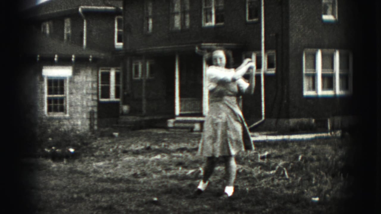 In New Cumberland, Pennsylvania, a woman in a 1940s-style dress prepares a golf swing in a backyard with a brick house behind her.