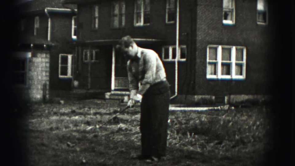 Adult man practices golf in a New Cumberland yard, with a brick house and windows behind him in 1946 home-movie footage.