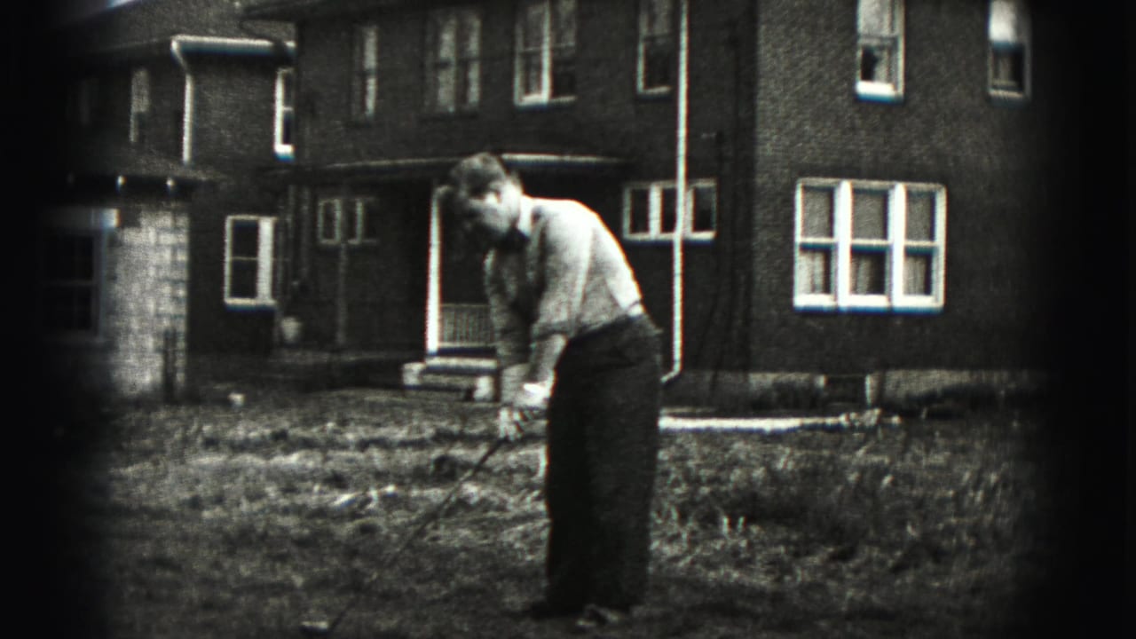 The man continues his golf practice in the New Cumberland yard, seen in soft black-and-white 8mm footage.