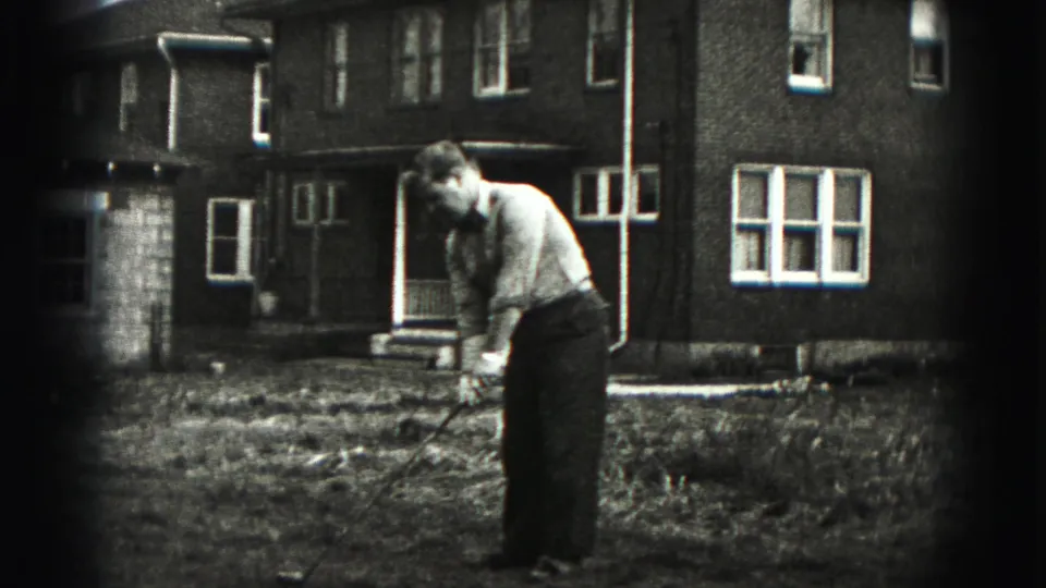 The man continues his golf practice in the New Cumberland yard, seen in soft black-and-white 8mm footage.
