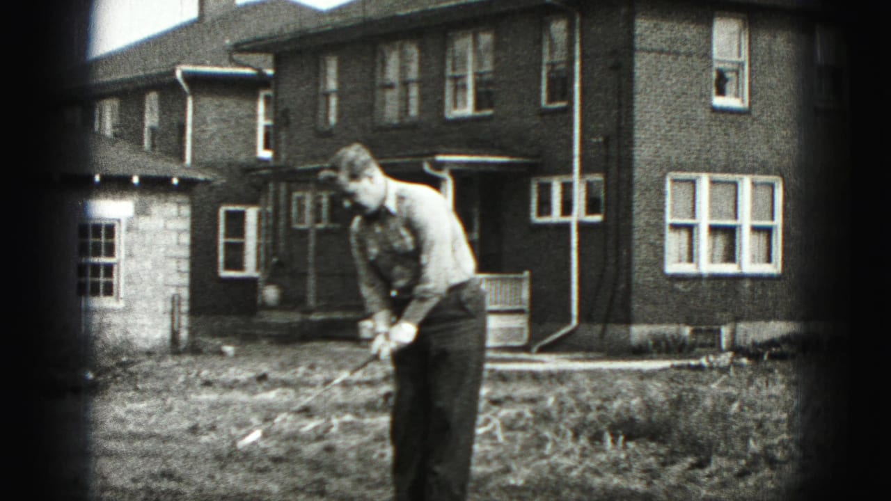 A man practices a golf swing in the front yard of a brick home in New Cumberland, Pennsylvania, in 1946 footage.